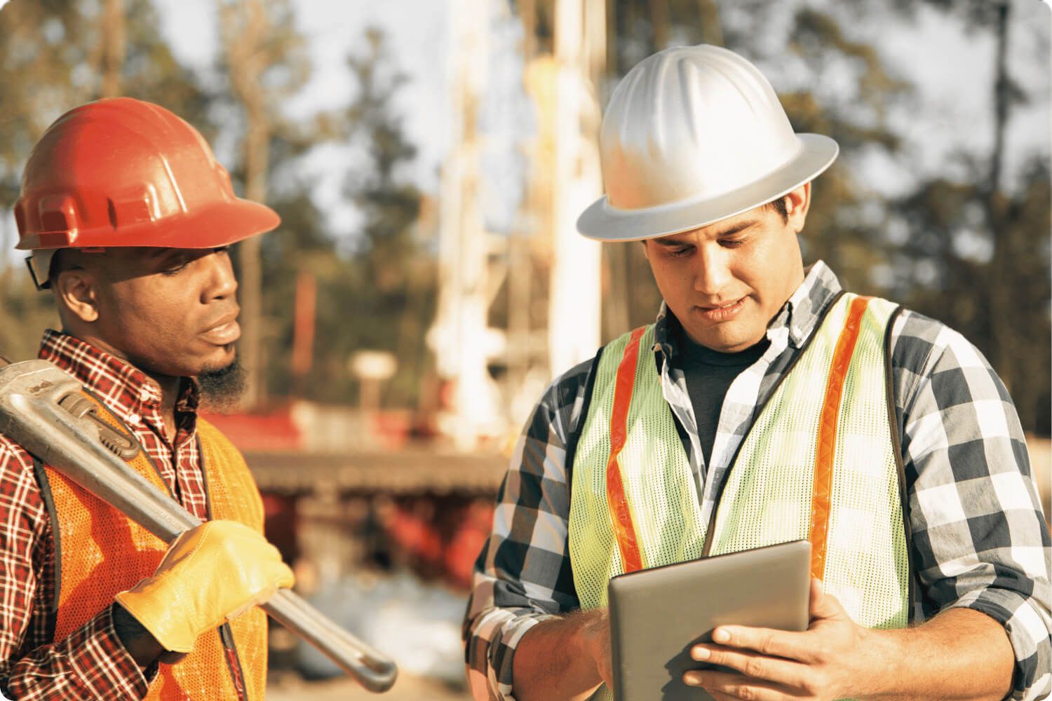 Workers in Hard Hats Looking at a Tablet